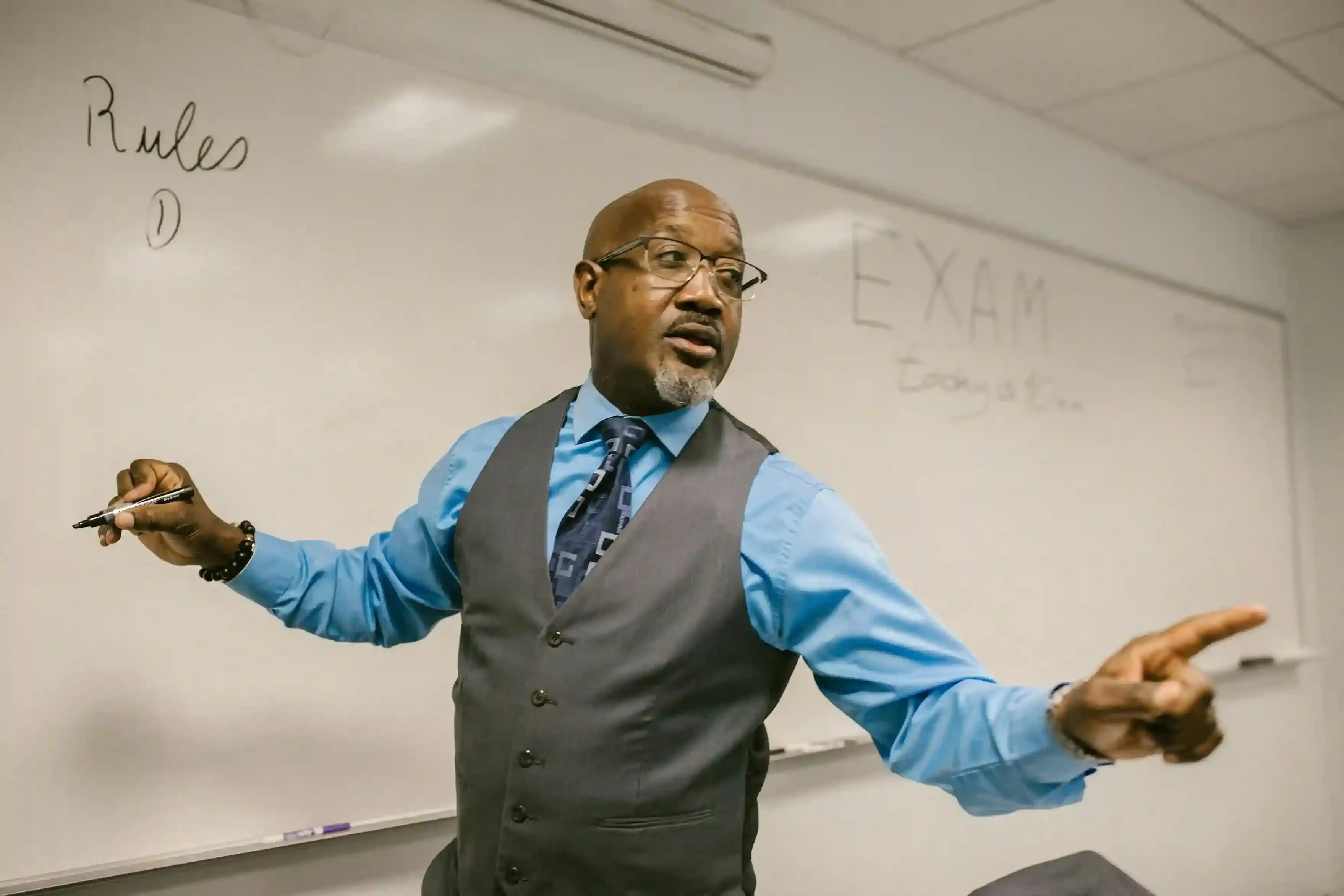 Instructor speaking in front of a classroom whiteboard during a professional English lesson